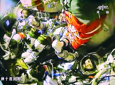 图为3位航天员手拉手庆祝成功。